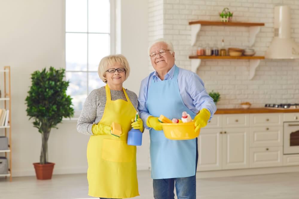 A senior couple happily engaging in spring cleaning, following a guide for seniors