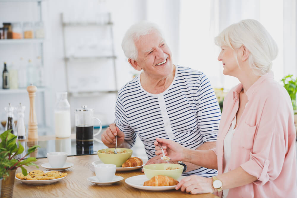 Spouse supporting an elderly Alzheimer's patient during a meal, overcoming eating challenges in Alzheimer's care.