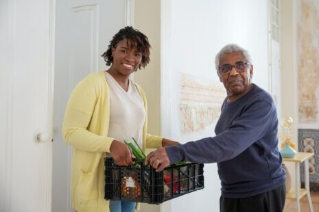 A homemaker assists an elderly man with griceries