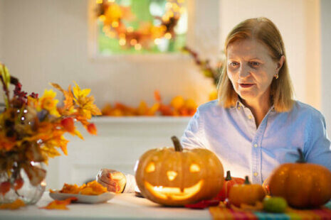 A woman gazes at a jack-o-lantern as she follows recommended Halloween safety tips for those with dementia.