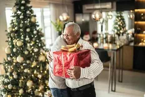 An elderly man receives a christmas gift.