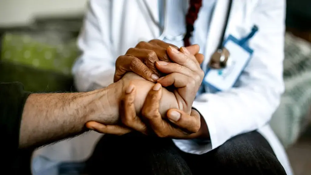 Doctor holding hands with a patient to help consider hospice.