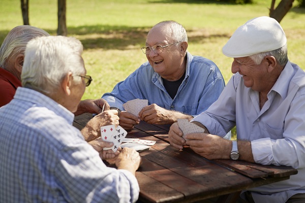 Retired men playing cards at park for self care
