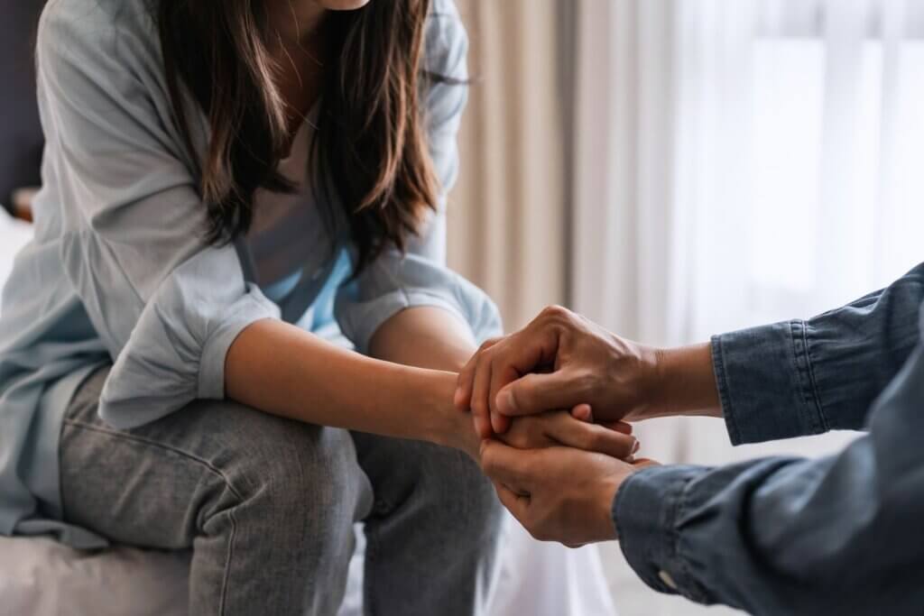 A couple holding hands to provide emotional support to someone in hospice care.