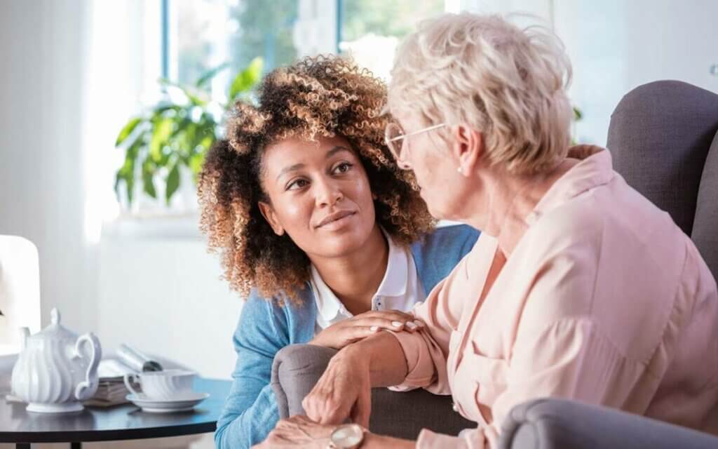 A compassionate caregiver attentively listening to an elderly person with dementia, signifying the depth of care and understanding required in dementia support.