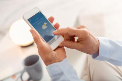 A senior checking the weather on a phone to help manage weather changes and maintain their routine.