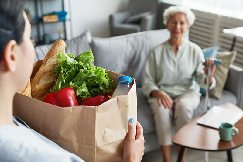 Caregiver Delivering Groceries to Senior Woman