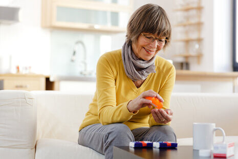 Woman smiling and looking at medicine, happy because her incontinence may be treatable.