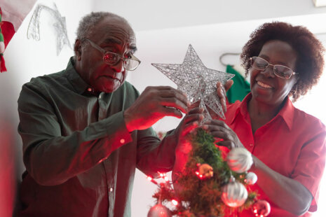 A woman helps her elderly father put up safe holiday decorations.