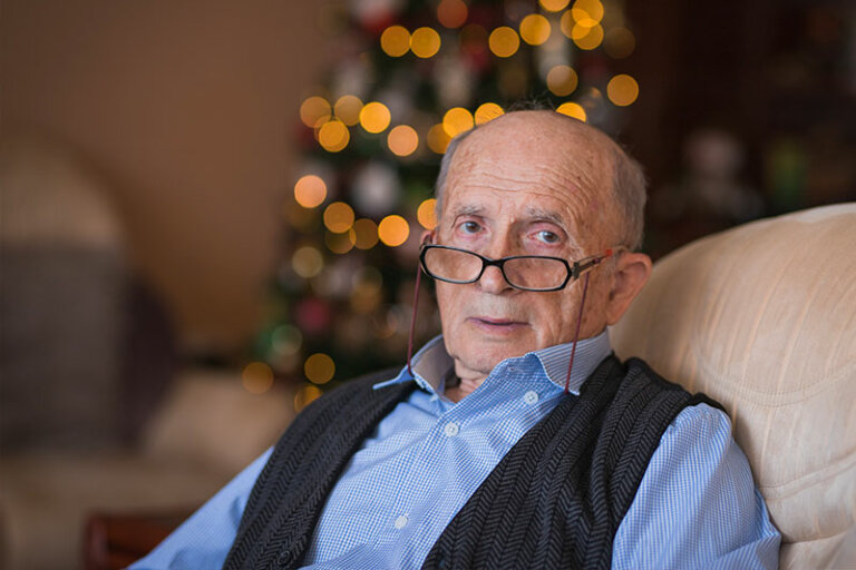Seasonal affective disorder in seniors is common, and it’s impacting this older gentleman who stares with a blank expression in front of holiday decorations.