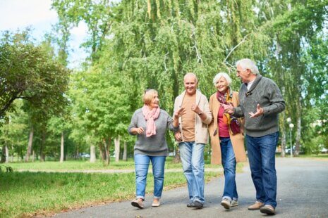 Elderly woman smiling while walking with friends outdoors, representing New Year resolutions for seniors.