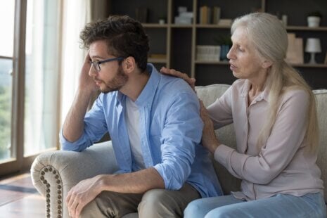 caregiver burnout during the holidays — adult son looking stressed while helping his aging mother at home during the holiday season
