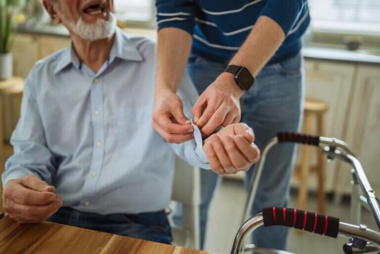 Caregiver assisting elderly person with Parkinson's disease during morning routine at home