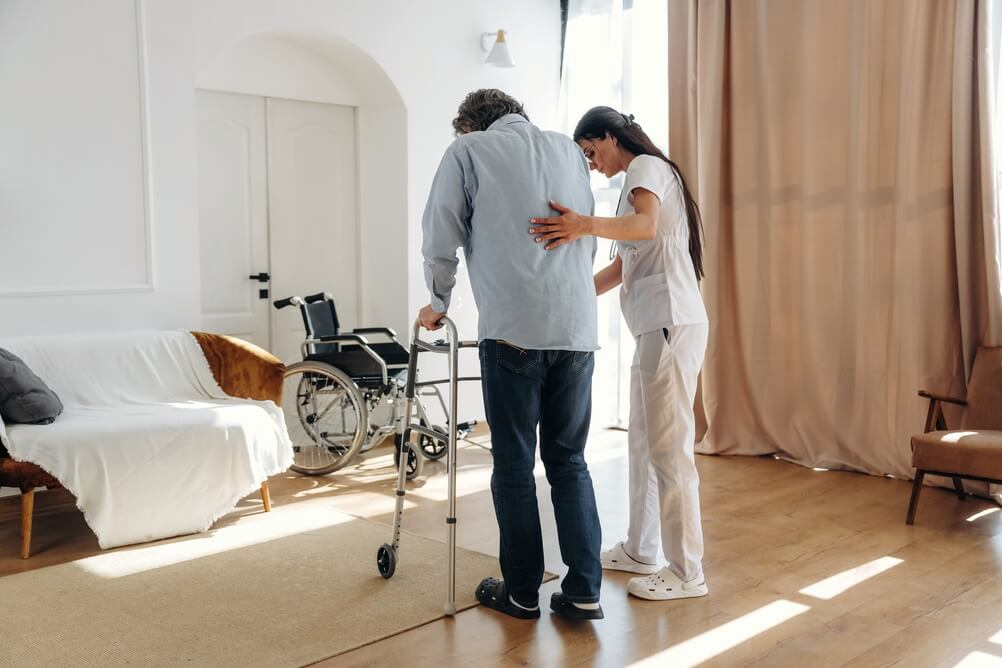 caregiver helping elderly parent settle in at home after going home after a hospital stay