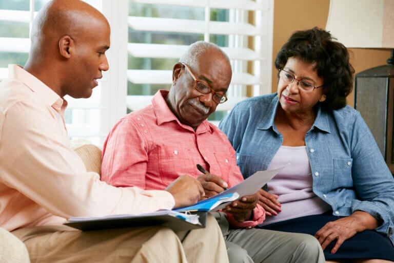 Care consultant and seniors reviewing a home care plan together at the kitchen table