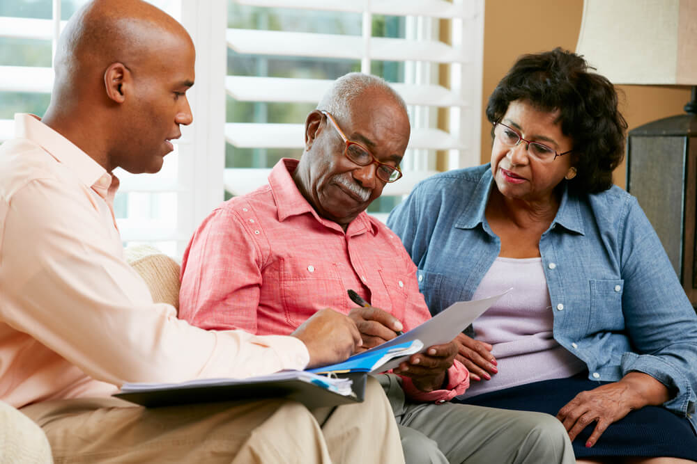 Care consultant and seniors reviewing a home care plan together at the kitchen table